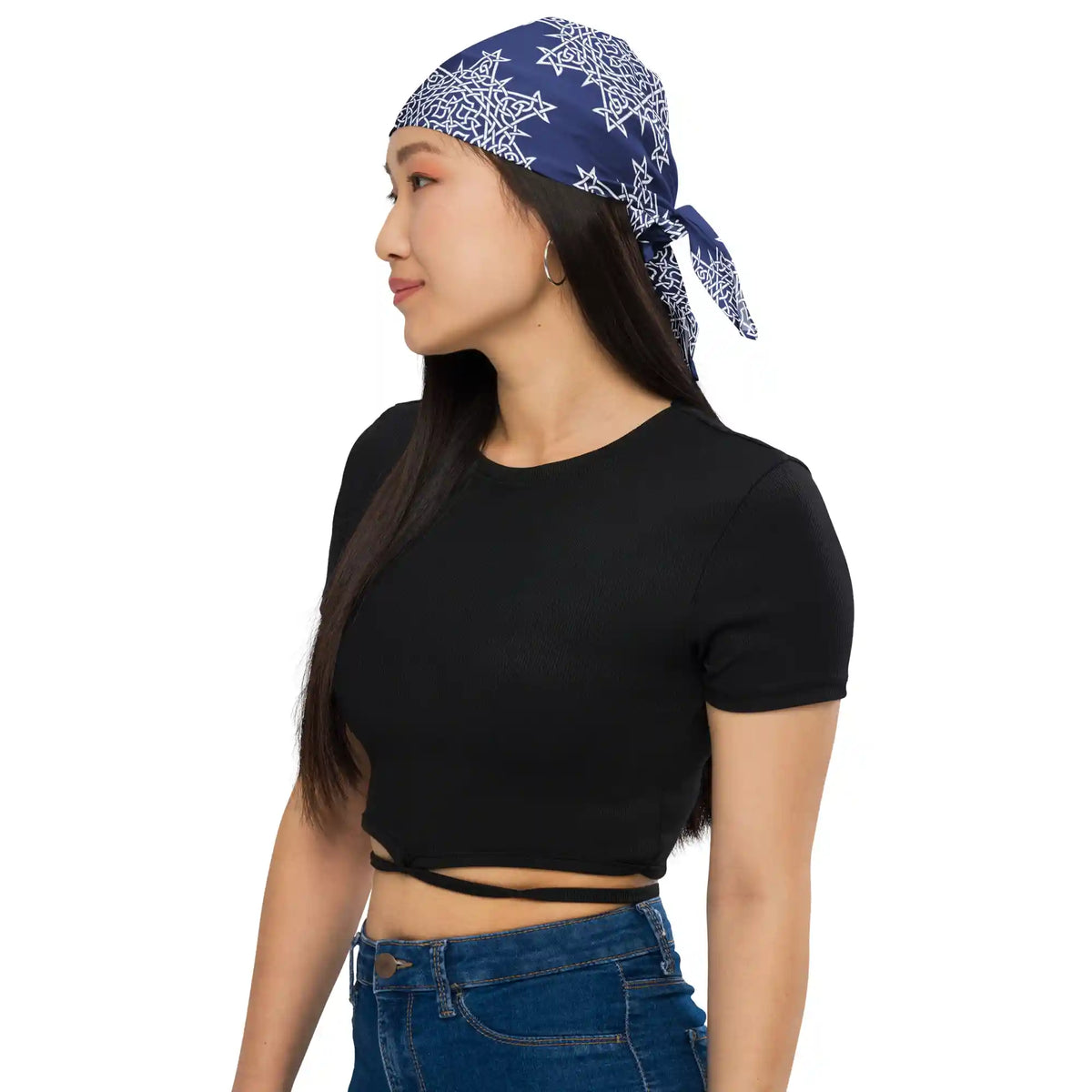 A young woman wearing a black crop top and blue jeans with a Xigfireon bandana adorned with the Navy Blue and White patterned series of the Morning Star Fire Celtic knot design.