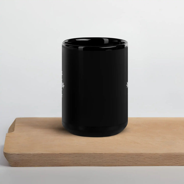 A Xigfireon black glossy 15oz mug featuring the Black & White Solid iteration of the Morning Star Fire Celtic knot design sitting on a cutting board. This Celtic knot symbolizes Father Sun.