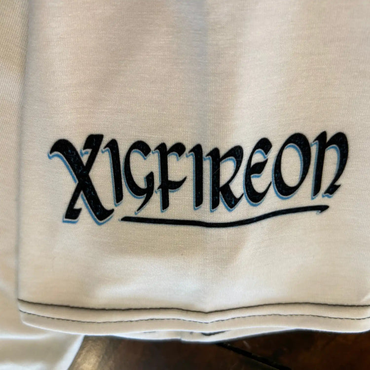 A close-up of the sleeve logo on a white Xigfireon graphic mens t-shirt featuring the Black Sunset iteration of the Morning Star Fire Celtic knot design.