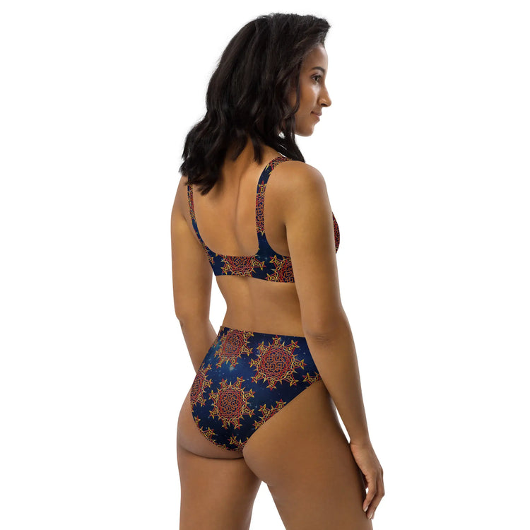 A woman, viewed from behind, wearing a Xigfireon graphic bikini featuring the Fire Colour Cosmos patterned series of the `Morning Star Fire` Celtic knot design.