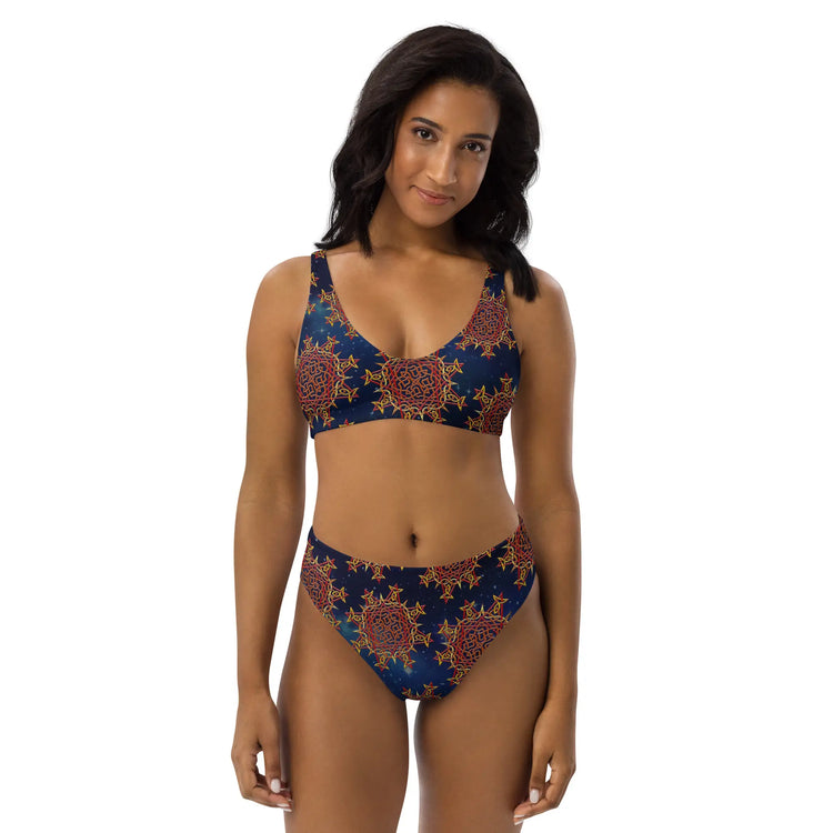 A woman, viewed from the front, wearing a Xigfireon graphic bikini featuring the Fire Colour Cosmos patterned series of the `Morning Star Fire` Celtic knot design.