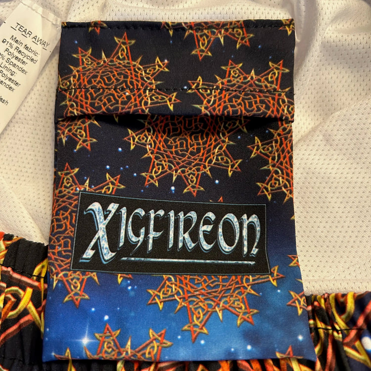 A close-up view of the inner pocket and logo on a pair of Xigfireon graphic swim trunks featuring the Fire Colour Cosmos (Small) patterned series of the `Morning Star Fire` Celtic knot design.