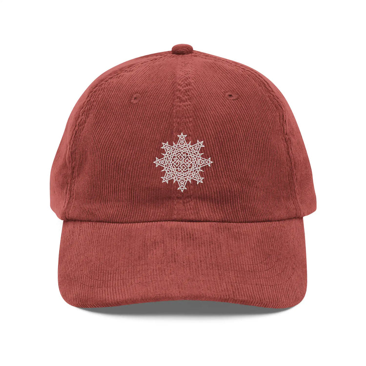 The front side of a burgundy Xigfireon vintage corduroy cap embroidered with the White iteration of the `Morning Star Fire` Celtic knot design.