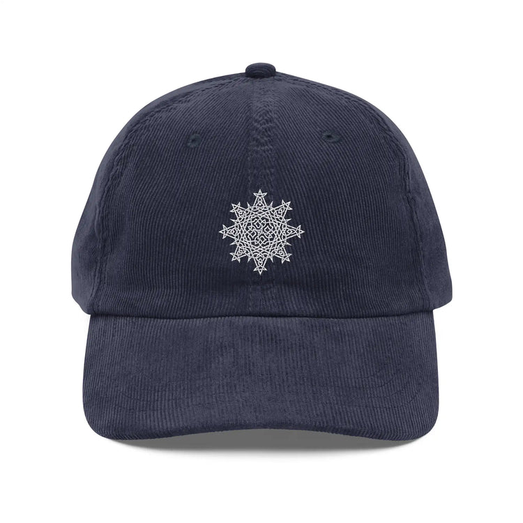 The front side of a navy blue Xigfireon vintage corduroy cap embroidered with the White iteration of the `Morning Star Fire` Celtic knot design.