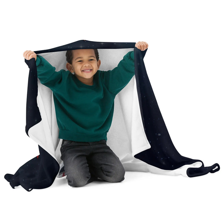 A young boy playing with a 50 inch by 60 inch Xigfireon throw blanket featuring the Eclipsed iteration of the `Morning Star Fire` Celtic knot design. Inspired by the 2023 Annular Solar Eclipse.