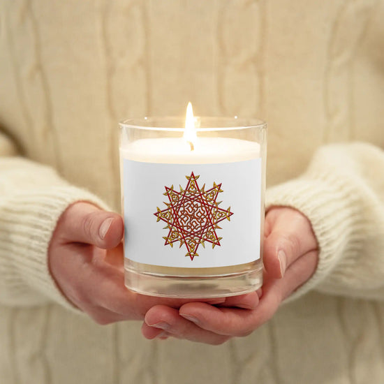 A persons hands holding a Xigfireon glass jar soy wax candle featuring the Fire Colour iteration of the `Morning Star Fire` Celtic knot design. The `Morning Star Fire` Celtic knot symbolizes Father Sun.