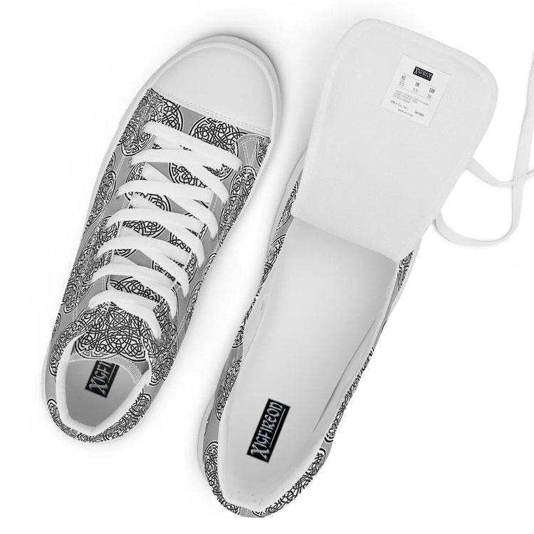 A view from above of a pair of Xigfireon canvas high tops featuring the Inverted Black & White Solid iteration of the `Reach Of The Spirit` Celtic knot pattern. The tongue on the right shoe is opened up to better reveal the inside of the shoe.