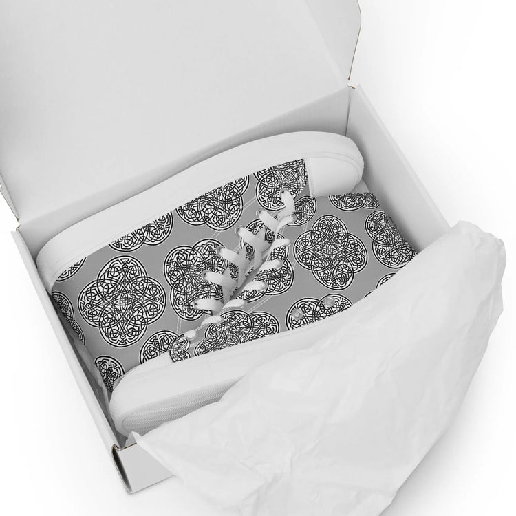 A shoebox containing a pair of Xigfireon canvas high tops featuring the Inverted Black & White Solid iteration of the `Reach of The Spirit` Celtic knot pattern.