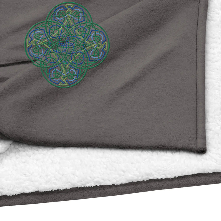 A close-up view of a heather grey Xigfireon sherpa blanket embroidered with the Living Colour iteration of the `Reach Of The Spirit` Celtic knot design.