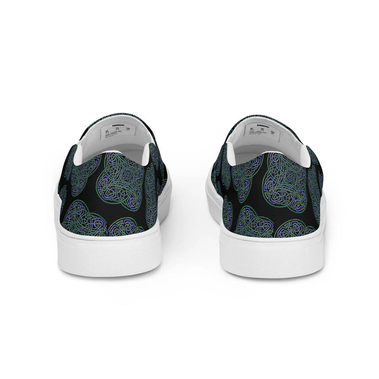 A view of the back of a pair of Xigfireon canvas slip-on shoes featuring the Living Colour on Black iteration of the `Reach Of The Spirit` Celtic knot pattern. The `Reach Of The Spirit` Celtic knot represents the Earth.