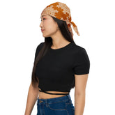 Woman wearing a black crop top and blue jeans with a Xigfireon bandana featuring Orange and White patterned series of the `Morning Star Fire` Celtic knot design.