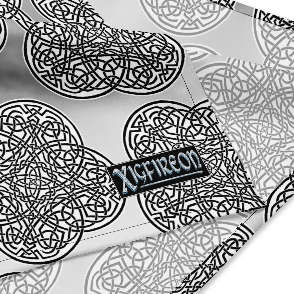 A close up view of the Xigfireon logo on a small sized (17.375 inch x 17.375 inch) Reach Of The Spirit Black and White Solid Forest Inverted bandana.