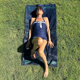 A young lady shown sunbathing on a Xigfireon beach towel featuring the Celestial iteration of the `Morning Star Fire` Celtic knot.