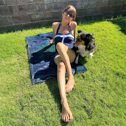 A young lady with her dog shown sunbathing on a Xigfireon beach towel featuring the Celestial iteration of the Morning Star Fire Celtic knot.
