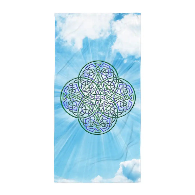 A Xigfireon bath and beach towel featuring the Living Colour on Sky iteration of the Reach Of The Spirit Celtic knot design displayed against a vibrant blue sky with drifting white clouds.