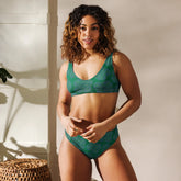 A woman, standing in a hallway, wearing a Xigfireon graphic bikini featuring the Living Colour Forest patterned series of the Reach Of The Spirit Celtic knot design.