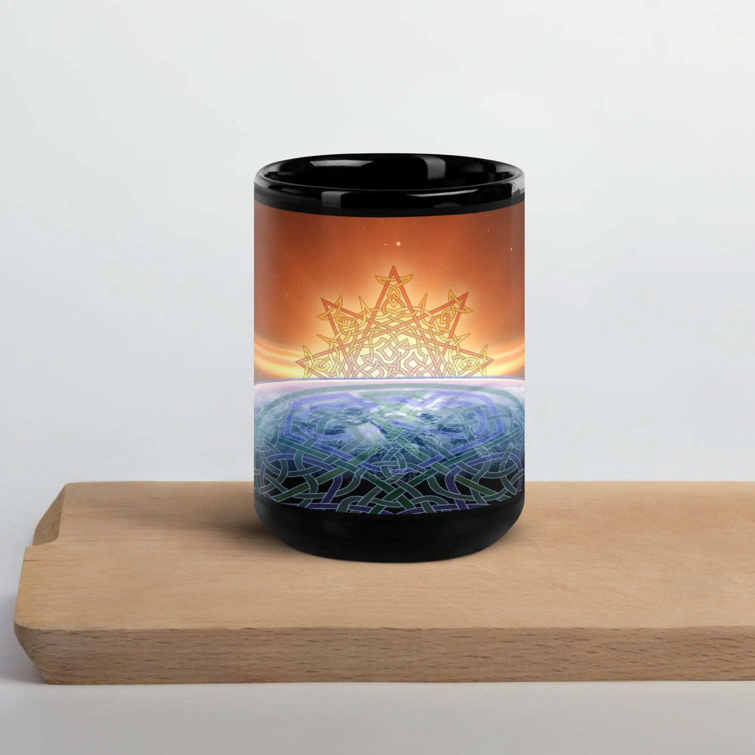 A cutting board underneath a 15oz Xigfireon black glossy graphic mug featuring the Derivation II Celtic knots merger design.