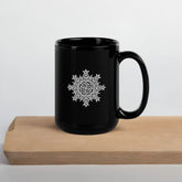 A cutting board beneath a Xigfireon black glossy 15oz mug featuring the Black & White Solid iteration of the Morning Star Fire Celtic knot design. This Celtic knot symbolizes Father Sun.