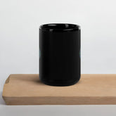 A cutting board displaying a Xigfireon black ceramic 15oz mug featuring the Living Colour iteration of the Reach Of The Spirit Celtic knot design. This Celtic knot symbolizes Mother Earth.