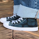 Canvas high top shoes worn with jeans, viewed from the side, featuring the Living Colour iteration of the Reach Of The Spirit Celtic knot pattern.