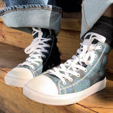 Canvas high top shoes worn with jeans, viewed from front left, featuring the Living Colour iteration of the Reach Of The Spirit Celtic knot pattern.