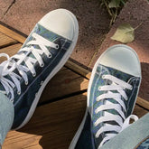 Canvas high top shoes worn with jeans, viewed from the top, featuring the Living Colour iteration of the Reach Of The Spirit Celtic knot pattern.
