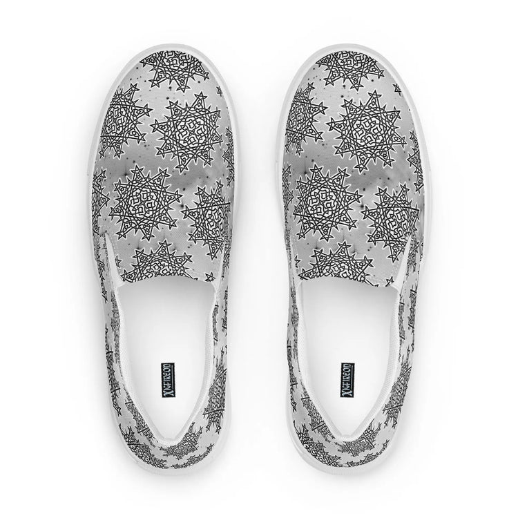 A view from above of a pair of Xigfireon canvas slip-ons featuring the Inverted Black & White Solid Cosmos iteration of the Morning Star Fire Celtic knot pattern. The Xigfireon logo is visible inside each shoe.