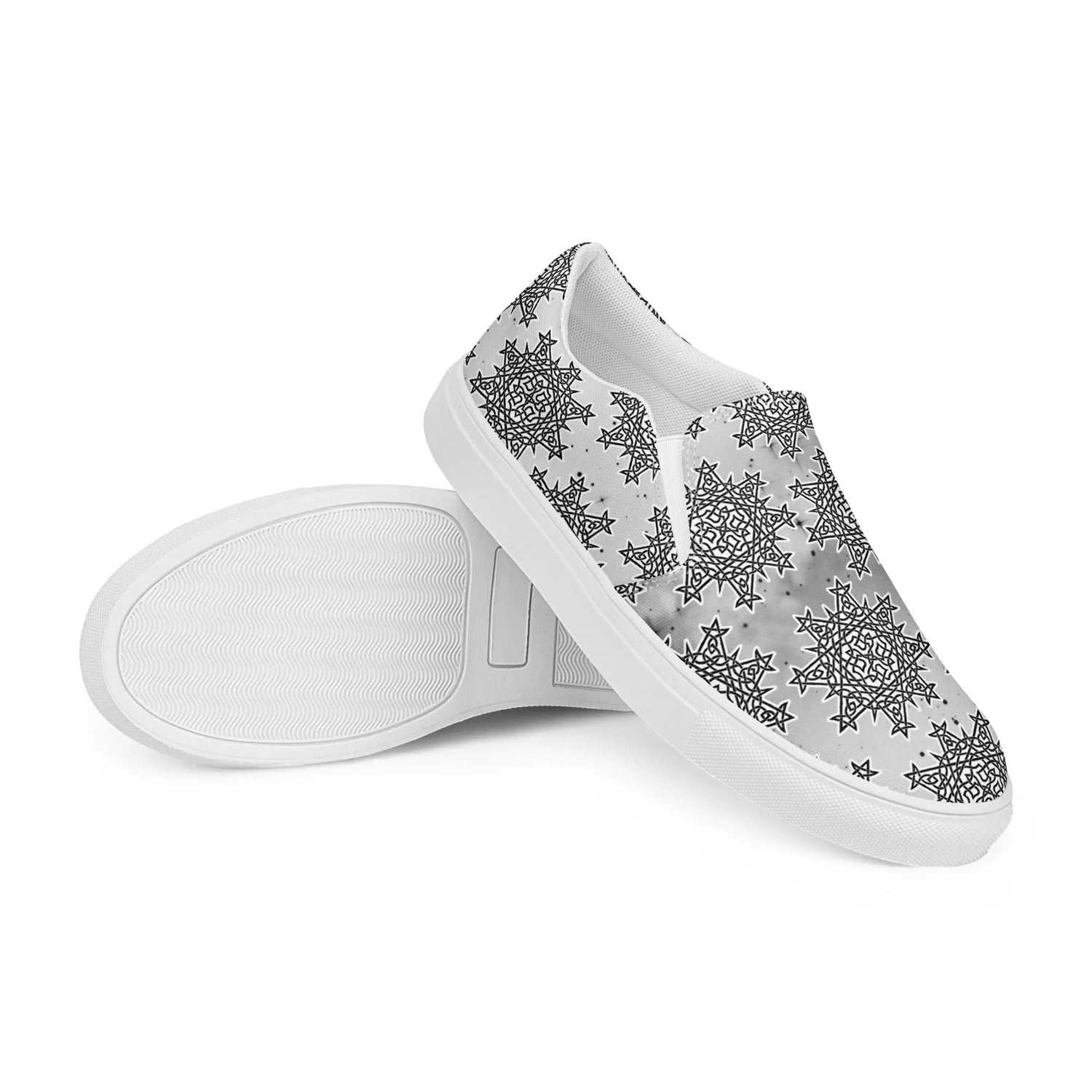 A pair of Xigfireon canvas slip-ons featuring the Inverted Black & White Solid Cosmos iteration of the Morning Star Fire Celtic knot pattern, with the left shoe positioned to reveal the tread pattern on the bottom of the sole.