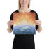 A young woman holding a 12 inch x 12 inch canvas print of the Derivation II Celtic knot design, which symbolizes the Sun and the Earth and their cosmic dance.