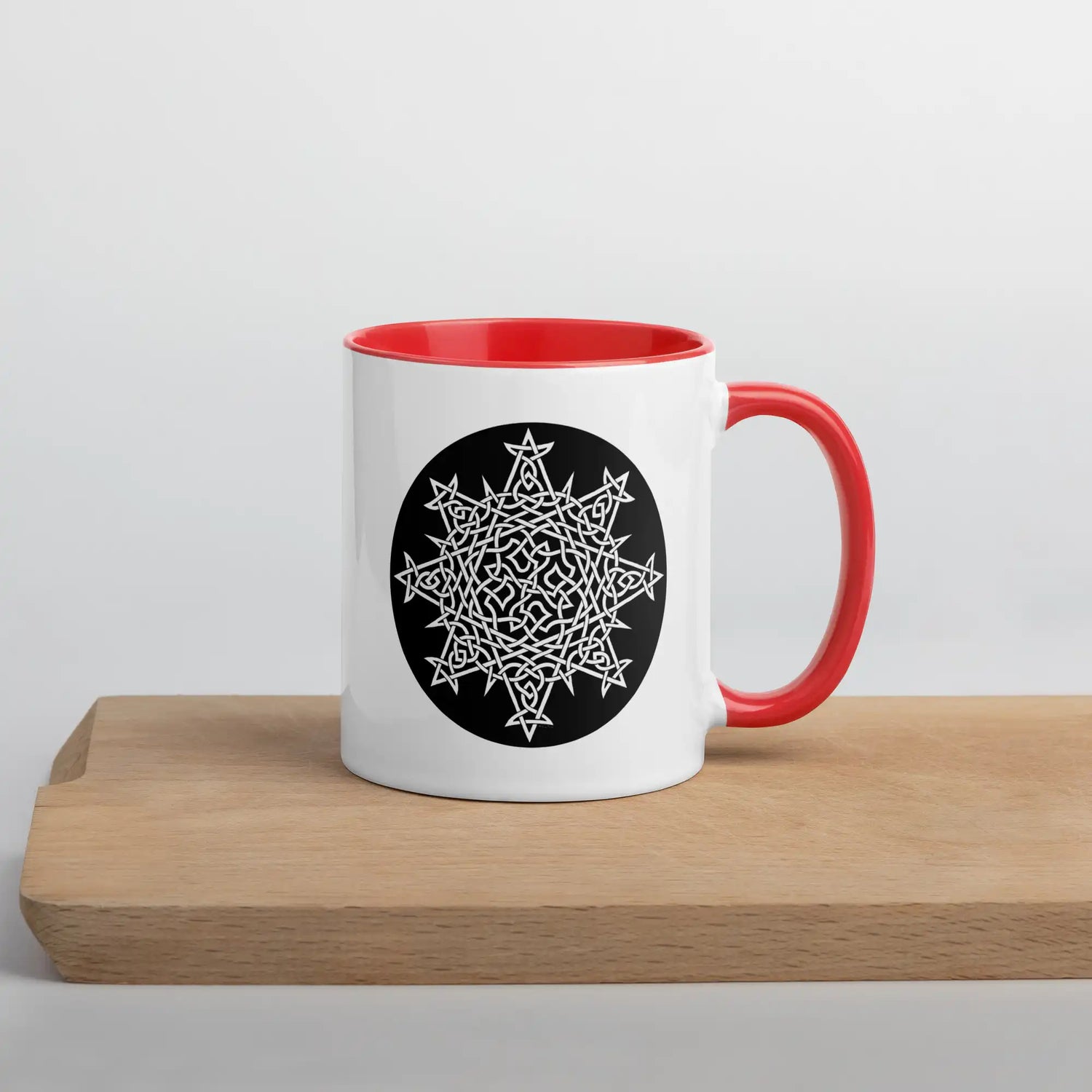 A Xigfireon white ceramic 11oz mug featuring the Black & White Circle iteration of the Morning Star Fire Celtic knot design, with red handle and inside. This Celtic knot symbolizes Father Sun.