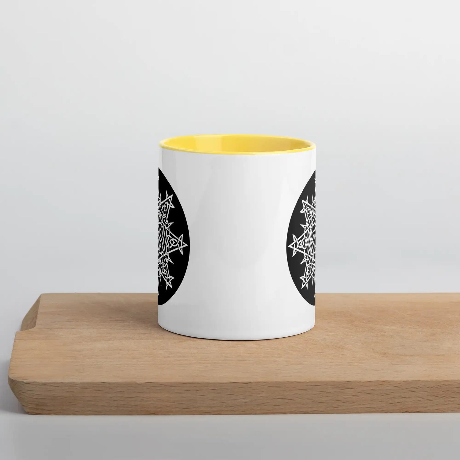 A Xigfireon white ceramic 11oz mug featuring the Black & White Circle iteration of the Morning Star Fire Celtic knot design, with yellow handle and inside. This Celtic knot symbolizes Father Sun.