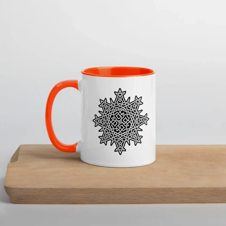 A cutting board displaying a Xigfireon white ceramic 11oz mug featuring the Black & White Solid iteration of the Morning Star Fire Celtic knot design, with orange handle and inside. This Celtic knot symbolizes Father Sun.
