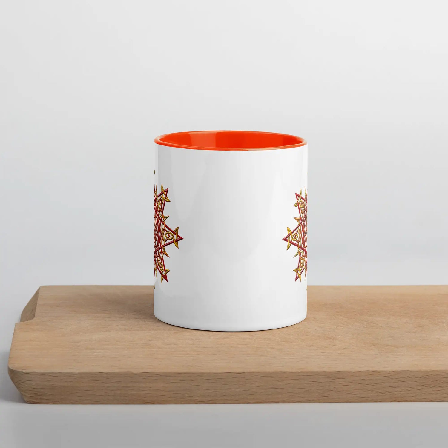 The front side of a Xigfireon white ceramic 11oz mug featuring the Fire Colour iteration of the Morning Star Fire Celtic knot design, with orange handle and inside. This Celtic knot symbolizes Father Sun.