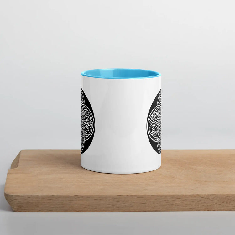 A Xigfireon white ceramic 11oz mug featuring the Black & White Circle iteration of the Reach Of The Spirit Celtic knot design, with blue handle and inside. This Celtic knot symbolizes Mother Earth.