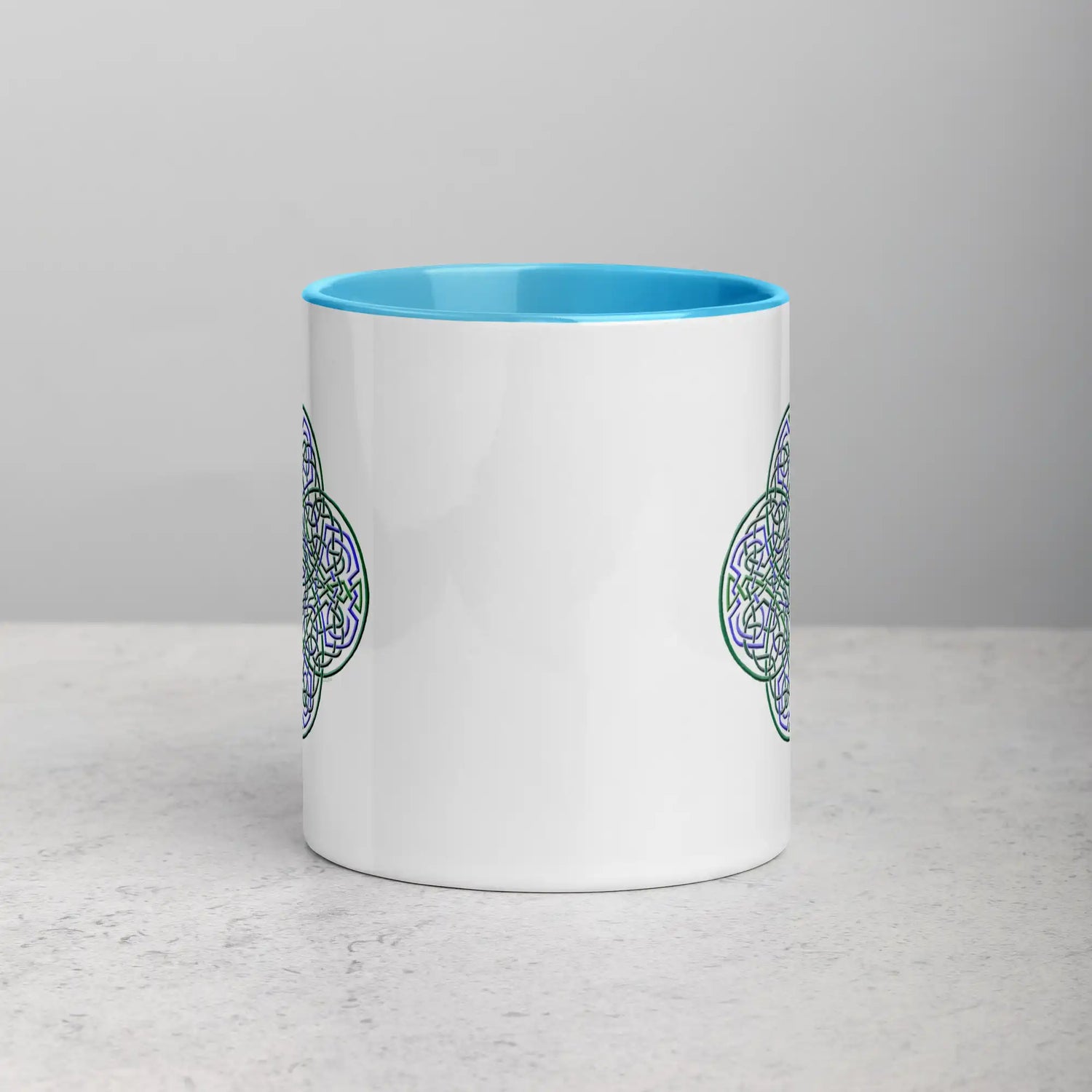 The front side of a Xigfireon white ceramic 11oz mug featuring the Living Colour iteration of the Reach Of The Spirit Celtic knot design, with blue handle and inside. This Celtic knot symbolizes Mother Earth.
