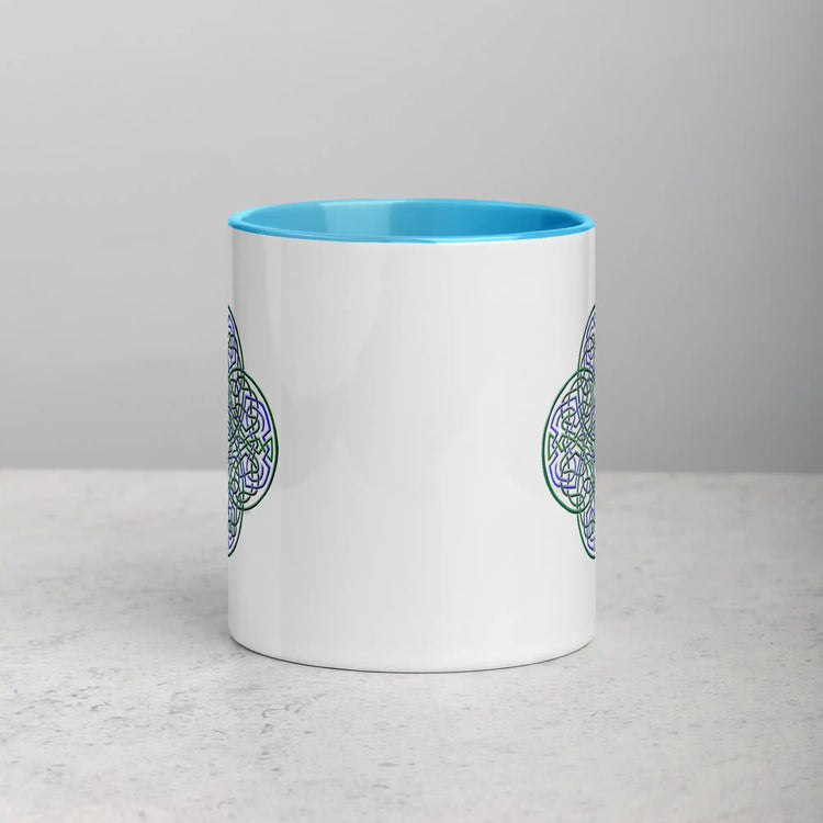 The front side of a Xigfireon white ceramic 11oz mug featuring the Living Colour iteration of the Reach Of The Spirit Celtic knot design, with blue handle and inside. This Celtic knot symbolizes Mother Earth.