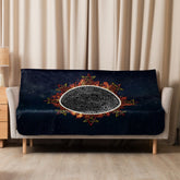 A sofa covered by a 50 inch by 60 inch Xigfireon sublimated sherpa blanket featuring the Eclipsed iteration of the Morning Star Fire Celtic knot design. Inspired by the 2023 Annular Solar Eclipse.