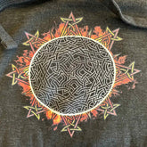 A close-up view of a charcoal heather grey Xigfireon graphic hoodie featuring the Eclipsed iteration of the `Morning Star Fire` Celtic knot design, inspired by the 2023 Annular Solar Eclipse.