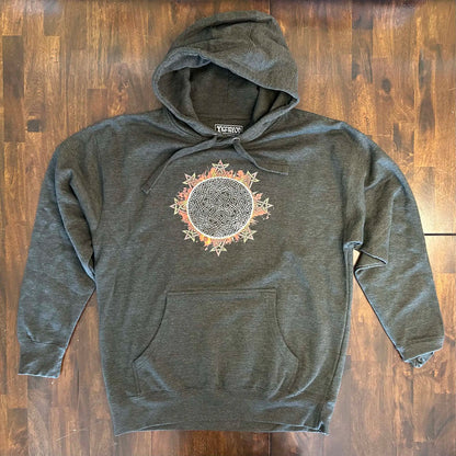 A wooden tabletop with a charcoal heather Xigfireon graphic hoodie featuring the Eclipsed iteration of the Morning Star Fire Celtic knot design, inspired by the 2023 Annular Solar Eclipse.