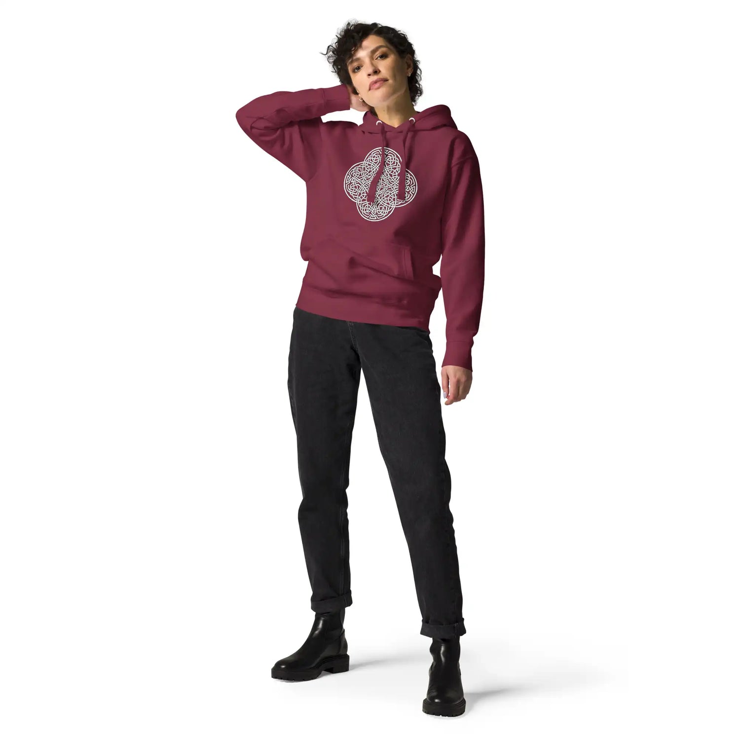 A young woman wearing a maroon Xigfireon graphic hoodie featuring the Black & White Hollow iteration of the Reach Of The Spirit Celtic knot design. The Reach Of The Spirit Celtic knot symbolizes the Earth.