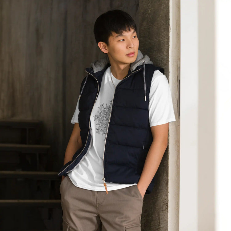 A young man, standing in a doorway, wearing a white Xigfireon graphic t-shirt featuring the Black & White Hollow iteration of the Morning Star Fire Celtic knot design. The Morning Star Fire Celtic knot symbolizes the Sun.