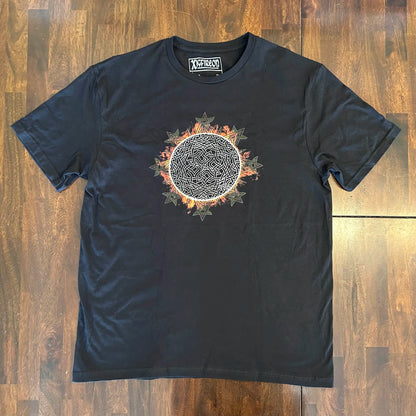 A wooden tabletop with a classic black Xigfireon graphic tee featuring the Eclipsed iteration of the Morning Star Fire Celtic knot design, inspired by the Annular Solar Eclipse of 2023.