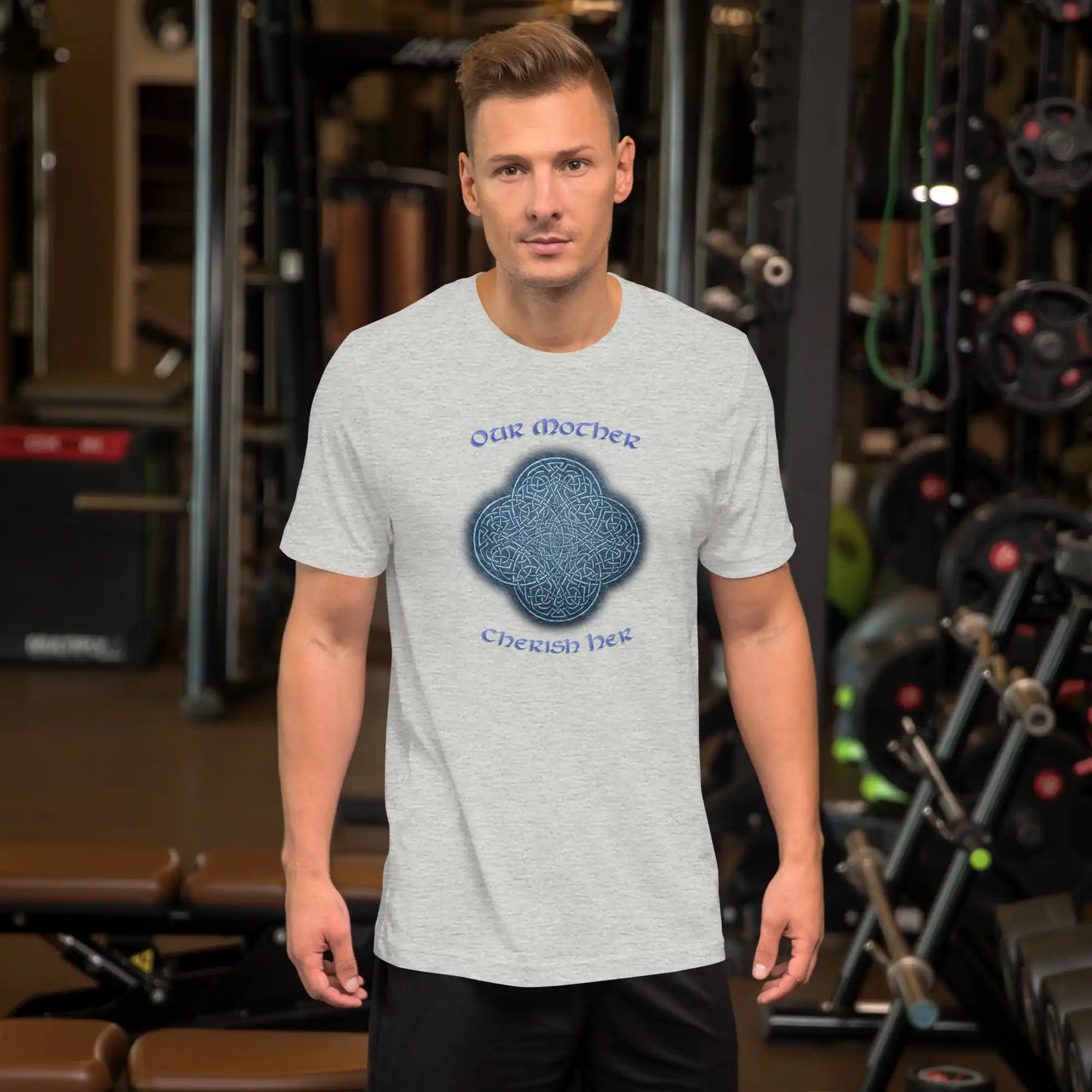 A young man wearing an athletic heather graphic t-shirt featuring the Blue Slate iteration of the `Reach Of The Spirit` Celtic knot design along with a message in a Celtic font: "Our Mother, Cherish Her".