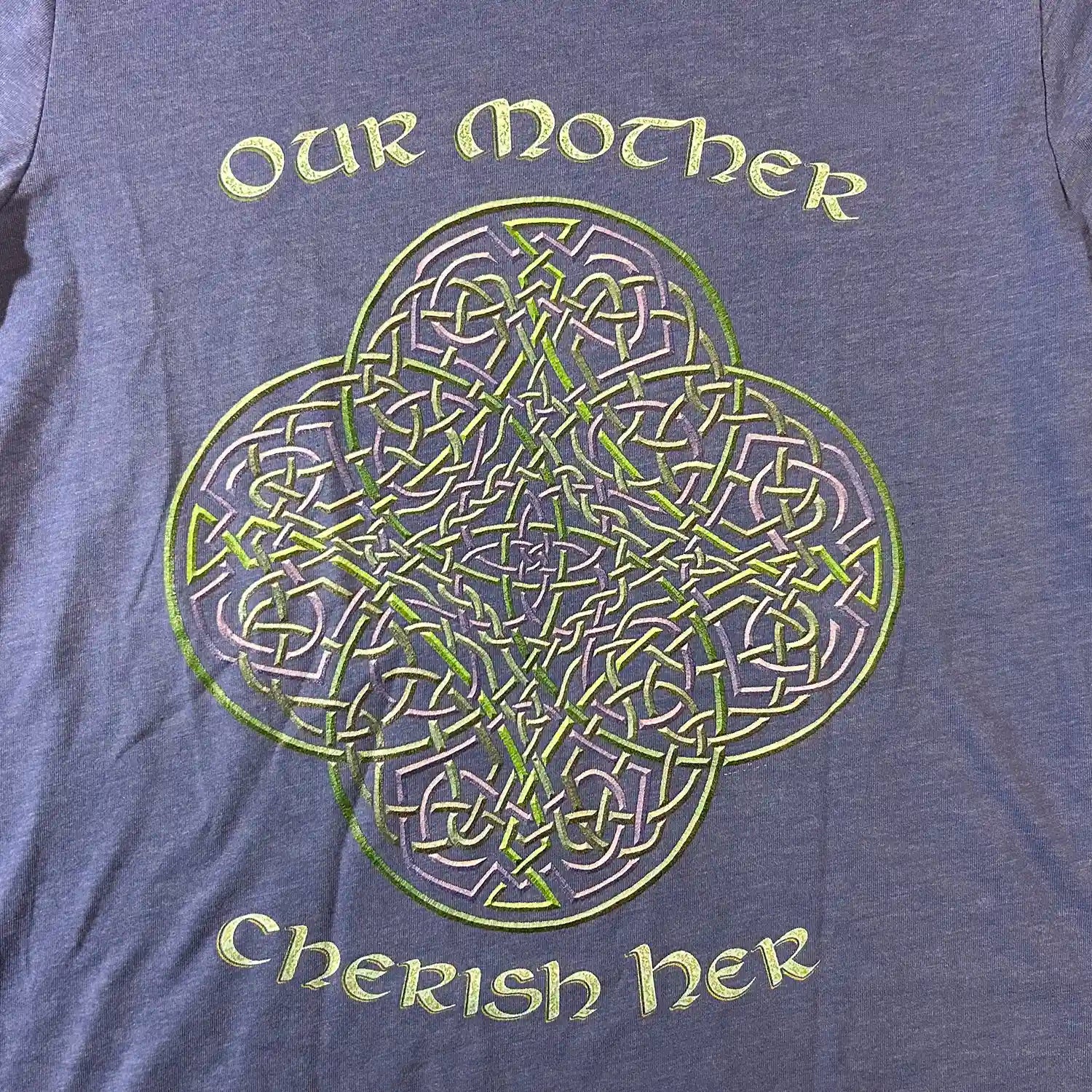 A close up view of a true royal blue Xigfireon graphic t-shirt featuring the Living Colour iteration of the Reach Of The Spirit Celtic knot design along with a message in a Celtic font: "Our Mother, Cherish Her".