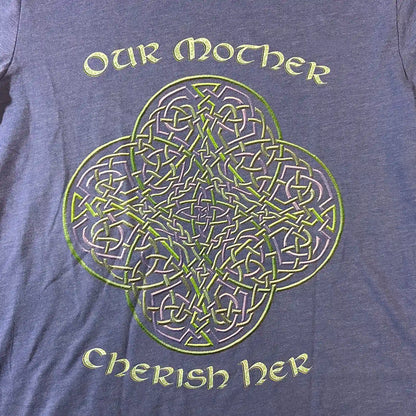 A close up view of a true royal blue Xigfireon graphic t-shirt featuring the Living Colour iteration of the Reach Of The Spirit Celtic knot design along with a message in a Celtic font: "Our Mother, Cherish Her".