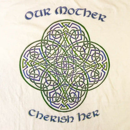A close up of a white Xigfireon graphic t-shirt featuring the Living Colour iteration of the Reach Of The Spirit Celtic knot design along with a message in a Celtic font: "Our Mother, Cherish Her".