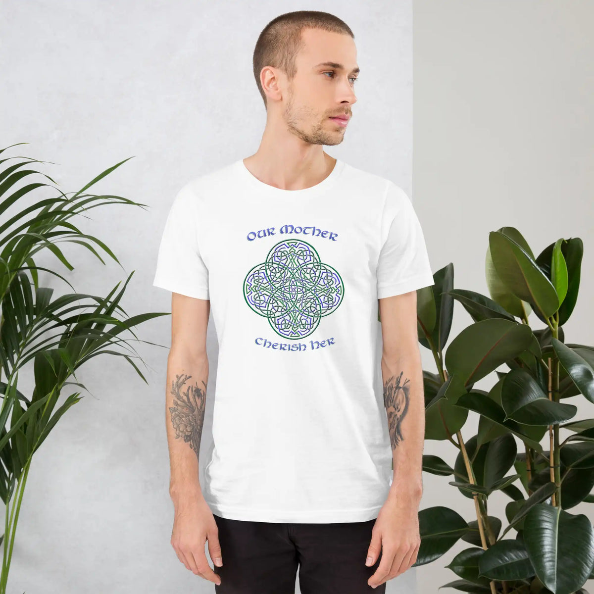 A young man wearing a white Xigfireon graphic t-shirt featuring the Living Colour iteration of the Reach Of The Spirit Celtic knot design along with a message in a Celtic font: "Our Mother, Cherish Her".