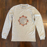 A wooden tabletop with an athletic heather Xigfireon long sleeve graphic tee featuring the Eclipsed iteration of the Morning Star Fire Celtic knot design, inspired by the 2023 Annular Solar Eclipse.