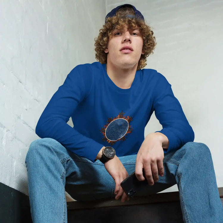 A young man wearing a true royal blue Xigfireon long sleeve graphic tee featuring the Eclipsed iteration of the Morning Star Fire Celtic knot design, inspired by the 2023 Annular Solar Eclipse.