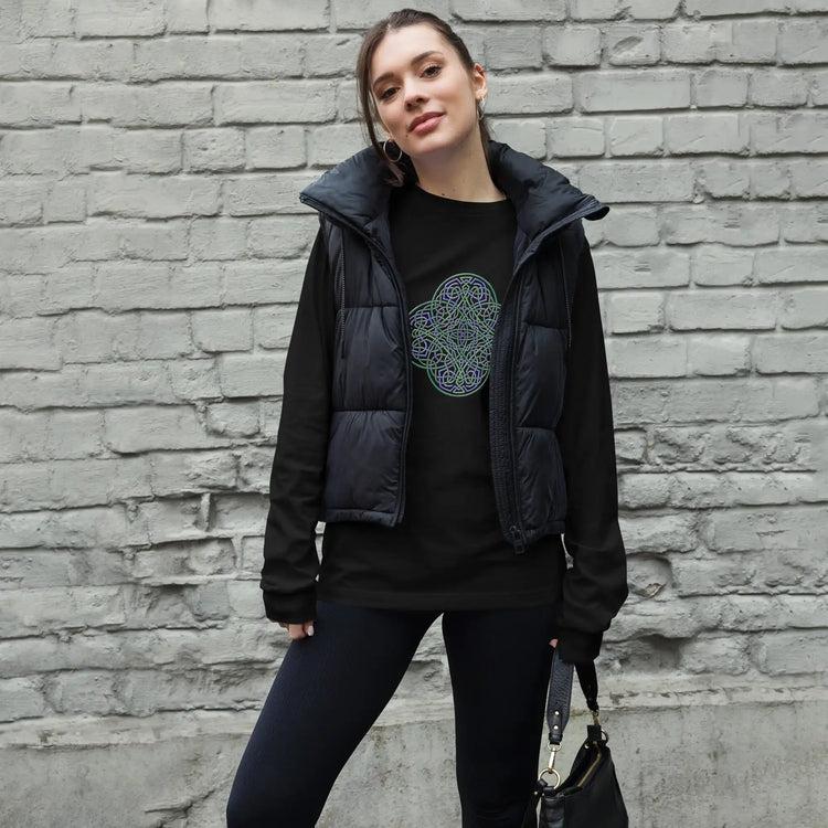 A young woman wearing a black Xigfireon long sleeve graphic t-shirt featuring the Living Colour iteration of the Reach Of The Spirit Celtic knot design. The Reach Of The Spirit Celtic knot symbolizes Mother Earth.